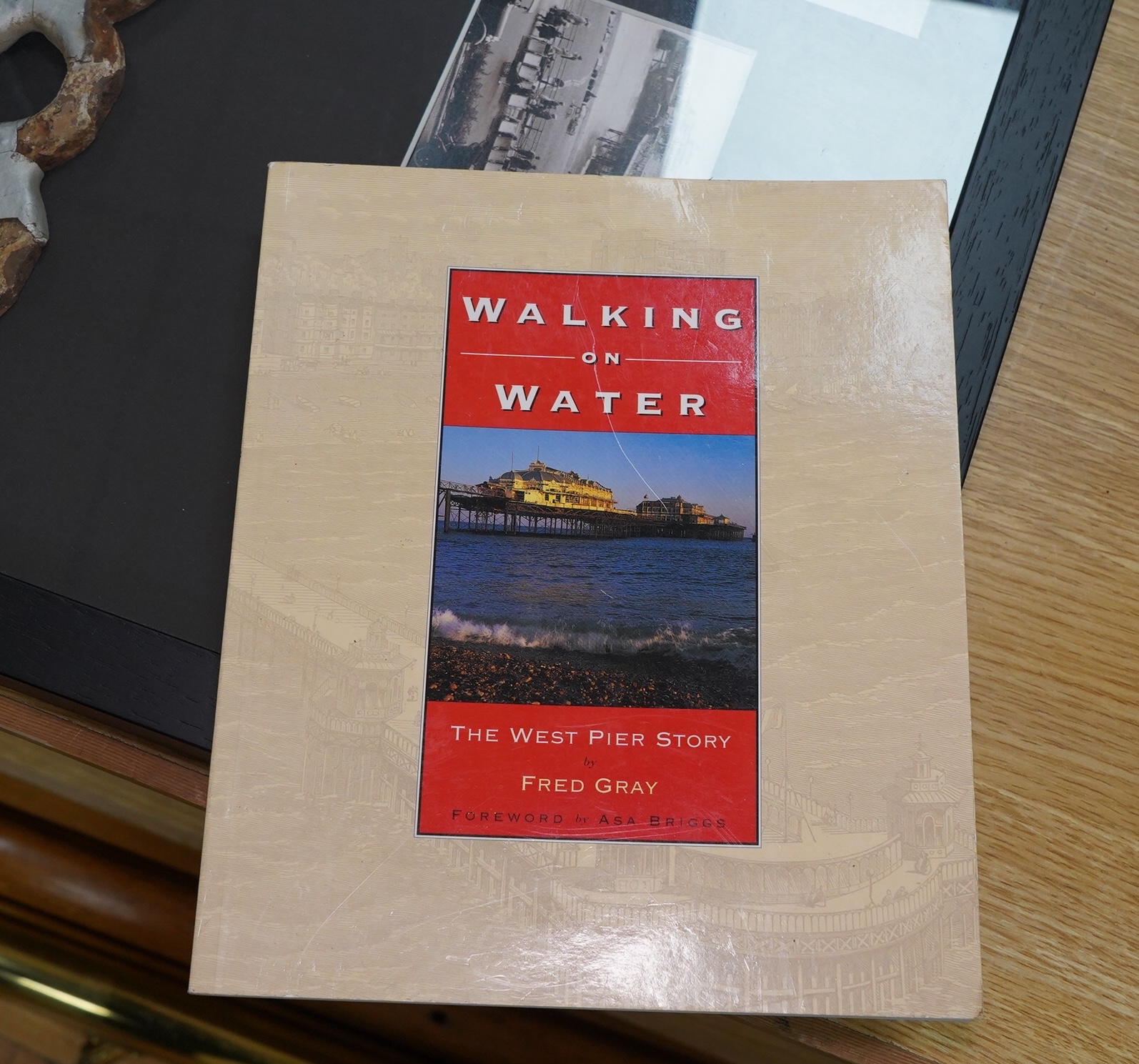 A framed part of the original frieze from the West Pier in Brighton, a photo and certificate, plus a book about the West Pier, 50cm wide, 40cm high. Condition - good